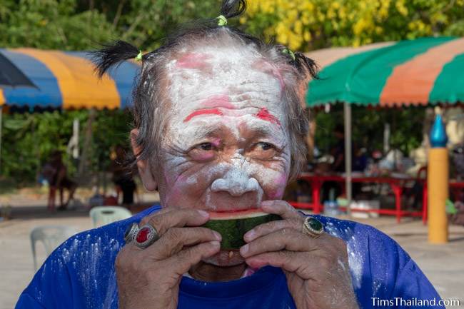 man with face painted eating watermelon